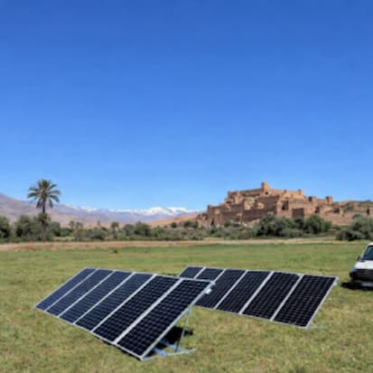 Panneaux photovoltaïques mobiles installés dans un paysage rural avec village en arrière-plan.